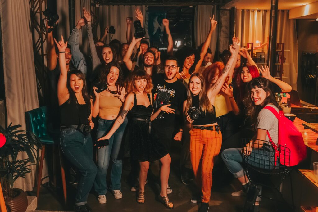 pexels-photo-3856042-3856042 High angle of excited young diverse friends in casual outfits with arms raised yelling happily while celebrating project success in modern workspace