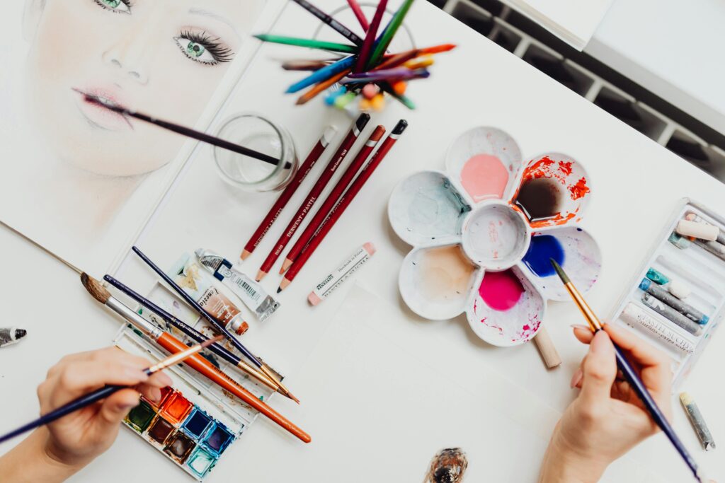 pexels-photo-4012974-4012974 Flat lay of art supplies, including brushes and paint, used in creating a colorful portrait.
